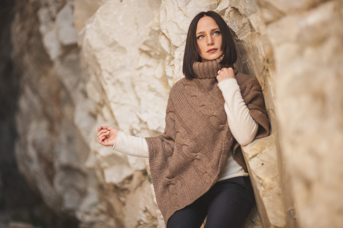Frau in einem Poncho aus Kaschmir von Dalle Piane Cashmere vor einer Felswand